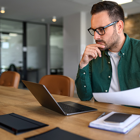 Focused young businessman auditing revenue reports and planning tax-efficient budgets in the office.