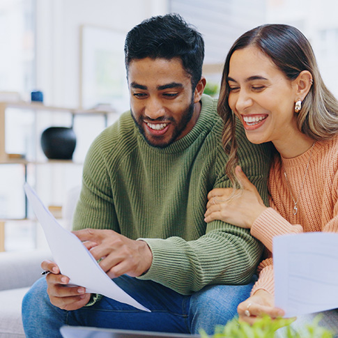 Happy couple reviewing tax documents at home, ensuring compliance and financial freedom.