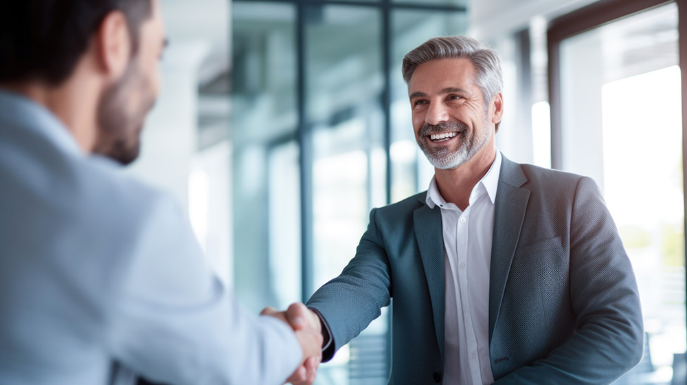 Smiling businessman shaking hands with a partner to discuss tax planning collaboration.