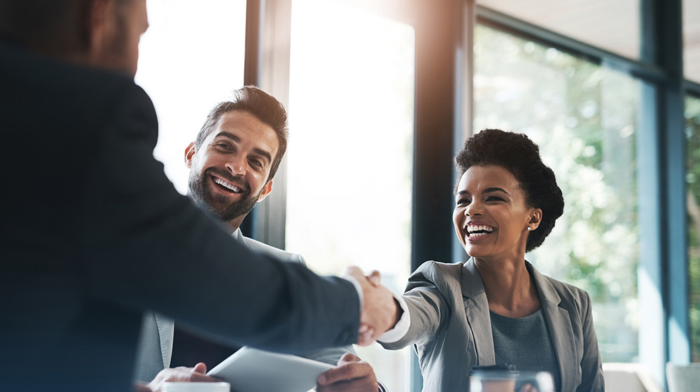 Business professionals shaking hands in a meeting, discussing tax planning and financial strategies.